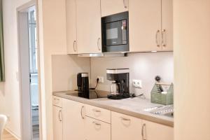 a kitchen with white cabinets and a black microwave at Pößnecker Werkstätten - Martin Luther in Pößneck
