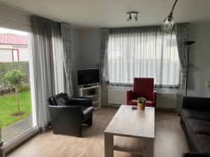 a living room with a couch and chairs and a tv at Meerchalets in Biggekerke