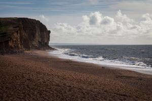 a beach with a cliff and the ocean at Barn Corner in Bridport