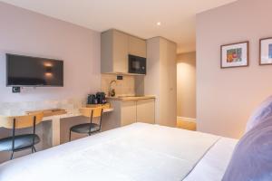 een slaapkamer met een bed en een keuken met een bureau bij Maison Letellier in Parijs