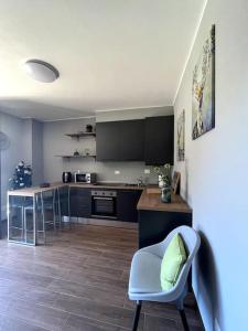 a kitchen with black cabinets and a blue chair at Sém chì, relaxing cottage in the mountains in Gromo