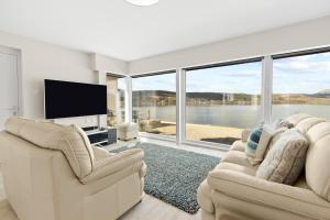 a living room with two chairs and a flat screen tv at Ferrypoint House in Rhu