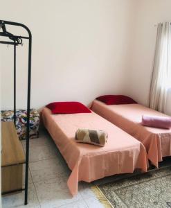 twee bedden in een kamer met roze lakens bij Casa-Sobrado próximo à Balsa de Ilha Bela e Rodoviária in São Sebastião