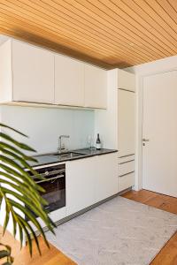 a kitchen with white cabinets and a sink at Luxus-Apartements direkt am Attersee in Seewalchen