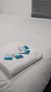 a white bed with four blue papers on it at Cosy Rooms in Ilford
