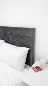 a white bed with a black headboard and a book at Cosy Rooms in Ilford