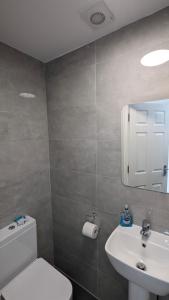 y baño con aseo blanco y lavamanos. en Cosy Rooms en Ilford