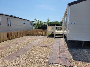 a yard with a house and a fence and a porch at A22 Holiday Resort Unity Brean Passes Included Sleeps 8 people 3 bedrooms No pets in Berrow