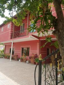 a pink building with tables and chairs in front of it at Hotel Flora in Çorovodë