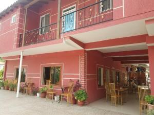 a red building with chairs and tables and a balcony at Hotel Flora in Çorovodë