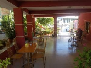 a restaurant with tables and chairs and a person sitting at a table at Hotel Flora in Çorovodë