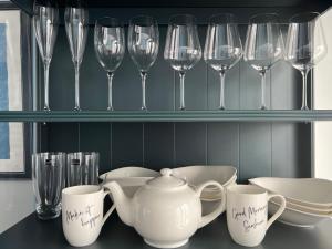 a shelf with wine glasses and a teapot and cups at A Stylish Flat Offering a Private Bedroom Near Landmark of Portsmouth in Portsmouth