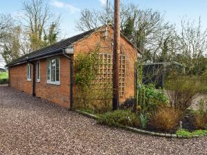 a small red brick building with a fence at Willow Wood Cottage 
