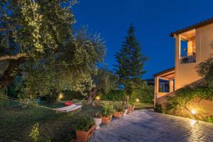 a backyard with a bench and trees at night at Villa Iliaktida - Private Villa with large Pool, Garden, Outdoor Kitchen & BBQ in Lithakia