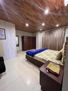 a bedroom with a large bed and a wooden ceiling at Blue sky Apartment in Nathia Gali