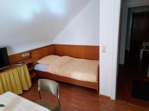 a small bedroom with a bed and a desk at Gästehaus Hirzel in Bad Wildbad