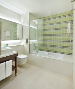 a bathroom with a tub and a toilet and a sink at Hyatt Place Dubai Baniyas Square in Dubai