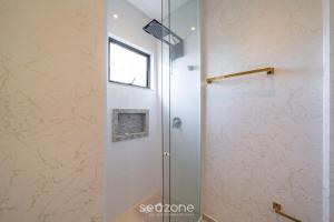 La salle de bains est pourvue d'une douche avec une porte en verre. dans l'établissement Belo Estúdio a 10min do mar em Meia Praia RGO0802, à Itapema