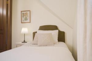 a white bed with a green headboard and white pillows at Karlamuiza Country Hotel in Kārļi