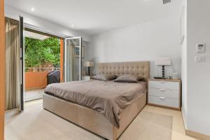 a bedroom with a large bed and a sliding glass door at Chic & Modern 2 Bed Apartment in Théoule-sur-Mer with Pool Access & Beach Proximity in Théoule-sur-Mer
