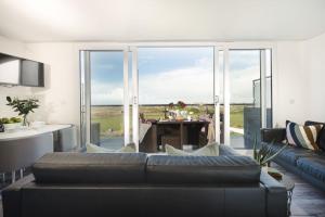 a living room with a couch and a table and glass doors at Beachview Apartment 4, Crantock, Newquay in Crantock