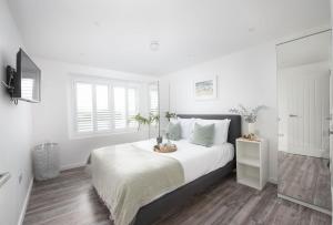 a white bedroom with a large bed with white pillows at Beachview Apartment 4, Crantock, Newquay in Crantock