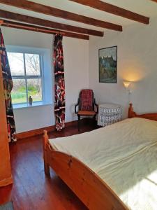 um quarto com uma cama, uma cadeira e uma janela em 381 Glassillaun Cottage em Renvyle