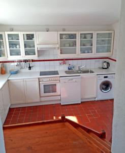 cocina con electrodomésticos blancos y suelo de baldosa roja en 381 Glassillaun Cottage, en Renvyle