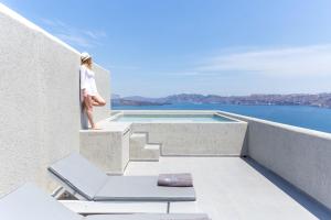 een vrouw op het balkon van een huis met zwembad bij Acroterra Rosa Luxury Suites & Spa in Akrotiri