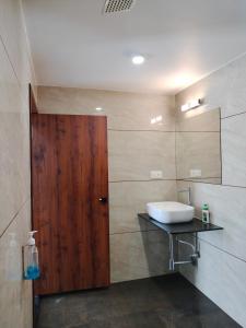 a bathroom with a sink and a wooden door at Unique Couple Friendly Stay in Morbi