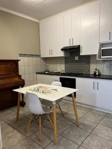 a kitchen with a white table and two chairs at Carstens Garden Cottages in Kimberley