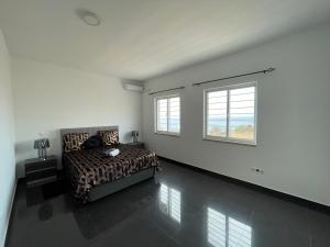 a bedroom with a bed and two windows at RESIDENCIAL EUNICE in Praia