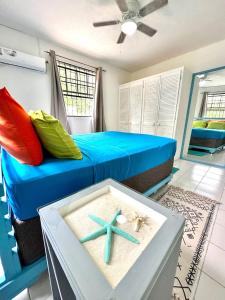 ein Schlafzimmer mit einem blauen Bett und einem Tisch mit einem Strandball in der Unterkunft South Coast Private on the Beach in Christchurch
