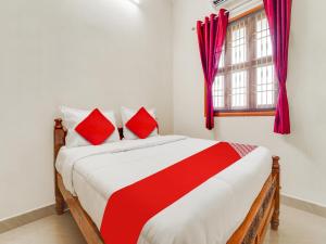 a bedroom with a bed with red pillows and a window at OYO KS Comfort in Chidambaram