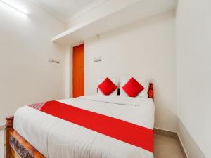 a bedroom with a bed with red pillows on it at OYO KS Comfort in Chidambaram