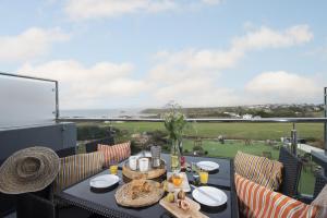 a dining table with a view of a golf course at Beachview Apartment 5, Crantock, Newquay in Crantock
