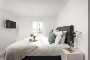 a white bedroom with a large bed with white pillows at Beachview Apartment 5, Crantock, Newquay in Crantock