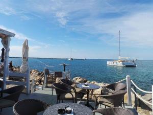 a patio with tables and chairs and a boat in the water at Apartment Crikvenica, Vinodol 2 in Crikvenica