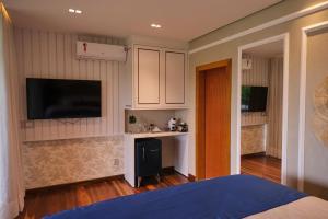 a room with a bed and a kitchen with a flat screen tv at Pousada Praia do Funil in Lajeado +53 photos