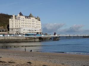 a large white building on the beach next to the ocean at DownTown - Manhattan House in Llandudno