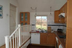 a kitchen with wooden cabinets and a sink and a window at 382 Claddaghduff Cottage in Claddaghduff