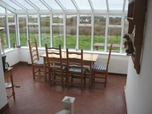 a dining room with a table and chairs in a conservatory at 382 Claddaghduff Cottage in Claddaghduff