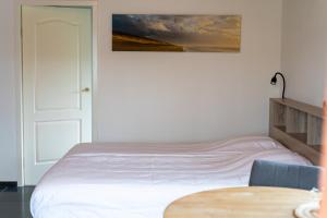 a white bedroom with a bed and a table at De Vrijheid-Melkstal in De Cocksdorp