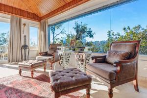 a living room with chairs and a table and a large window at SaffronStays Naiintara in Nainital