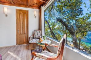 a dining room with a table and chairs and a large window at SaffronStays Naiintara in Nainital +64 photos