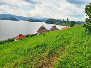 a group of huts on a hill next to a lake at African Tent Resort in Kabale