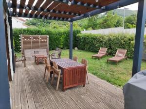 um deque de madeira com uma mesa e cadeiras e uma pérgola em Maison avec jardin au pied du Viaduc de Millau em Creissels