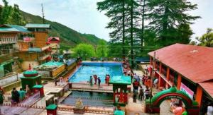 una piscina en un parque de atracciones con gente de pie alrededor en Jagatram Niwas en Dharamshala