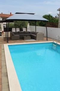 a large blue swimming pool with an umbrella over it at Apartmens Kimm II in Poreč