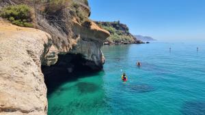 dos personas en el agua al lado de un acantilado en Apartament Burriana Beach SilHouse, en Nerja